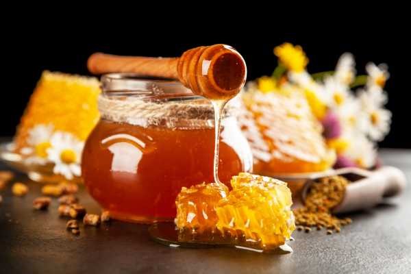 atmospheric image of clear honey with flowers in the background