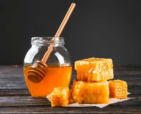 honey jar and dipper and chunks of honeycomb