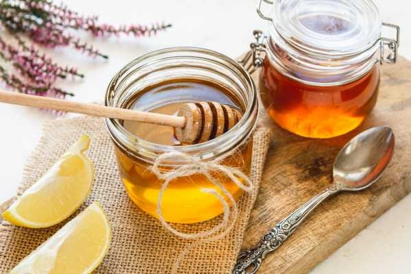 jar of honey tied with brown string, on a table with fresh honey comb