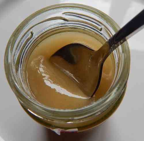 a jar of honey with a spoon Jar of soft set honey with spoon